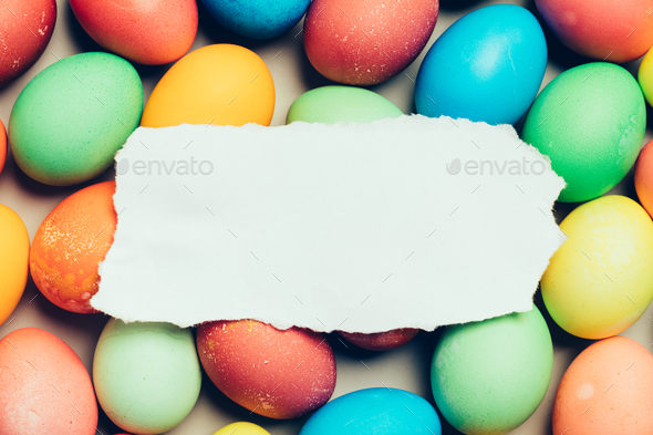 White paper laying on top of colorful eggs. - Stock Photo - Images