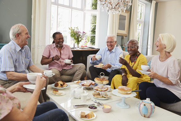 Group Of Senior Friends Enjoying Afternoon Tea At Home Together Stock Photo by monkeybusiness