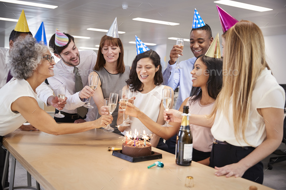 Colleagues celebrating a birthday in the office make a toast Stock Photo by monkeybusiness