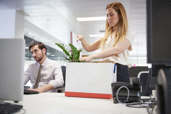Fired female employee packing box of belongings in an office Stock Photo by monkeybusiness