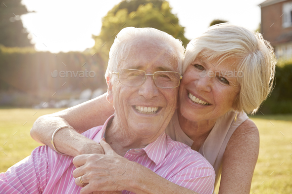 Senior couple in garden, smiling at camera, close up Stock Photo by monkeybusiness