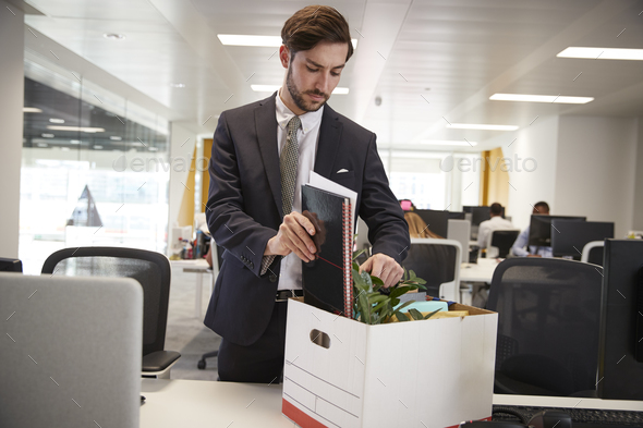 Fired male employee packing box of belongings in an office Stock Photo by monkeybusiness