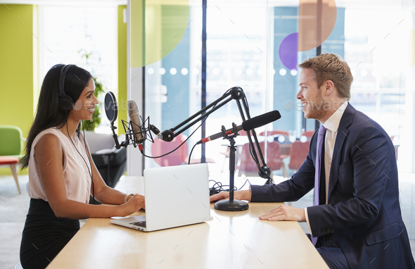 Young woman interviewing a guest in a studio for a podcast Stock Photo by monkeybusiness