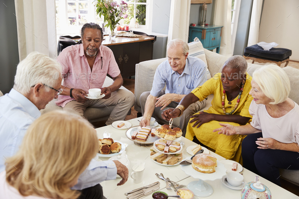 Group Of Senior Friends Enjoying Afternoon Tea At Home Together Stock Photo by monkeybusiness