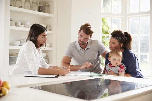 Family With Baby Meeting Financial Advisor At Home Stock Photo by monkeybusiness