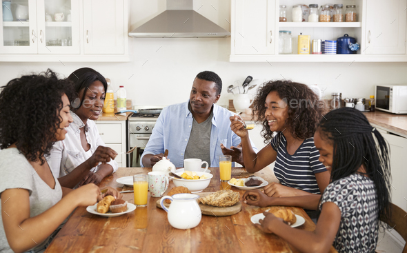 Family With Teenage Children Eating Breakfast In Kitchen Stock Photo by monkeybusiness
