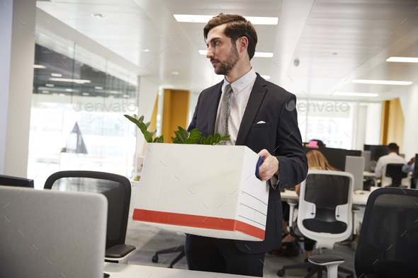 Fired male employee holding box of belongings in an office Stock Photo by monkeybusiness