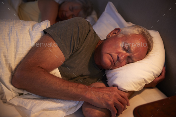 Peaceful Senior Man Asleep In Bed At Night Stock Photo by monkeybusiness