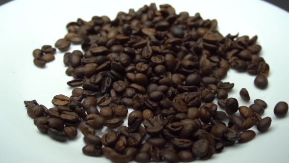 Coffee Beans Are Falling on the White Plate