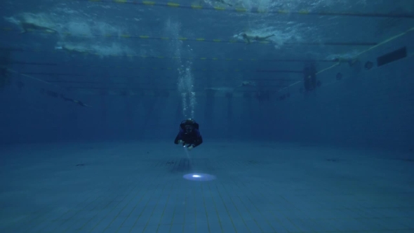 Scuba Diver Using Underwater Light During Training on Diving Lesson in Deep Pool alt