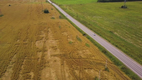 Flying Over Asphalt Road Between Farm Fields in Countryside