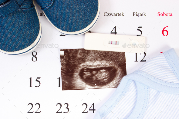 Pregnancy test, ultrasound scan of baby and clothing for newborn on calendar - Stock Photo - Images