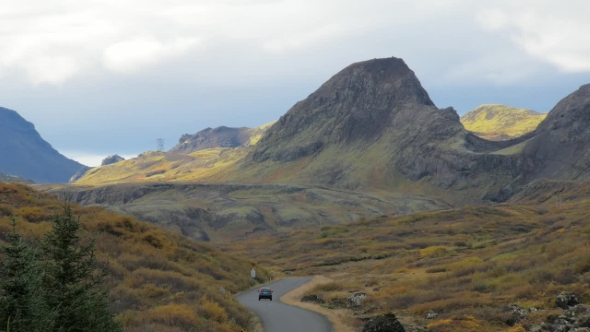 Unique Icelandic Landscape with Lava Field, Hills, Winding Road and Moving Car, in Autumn Day