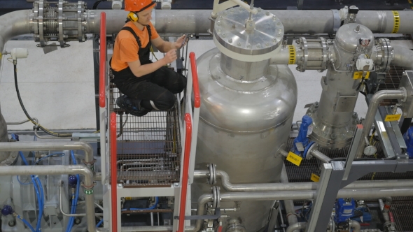 The Employee Is Monitoring the Compressor on the Top alt