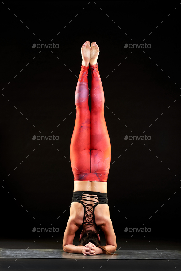 Woman doing headstand during a yoga workout - Stock Photo - Images