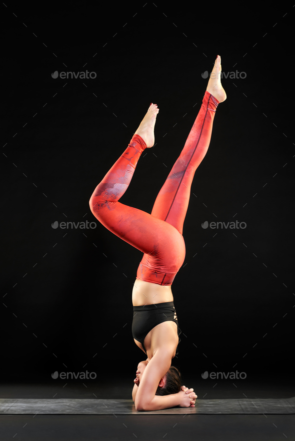 Woman working out on a yoga mat doing a headstand - Stock Photo - Images