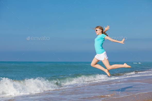 teen girl jumping on the beach at blue sea shore in summer vacat - Stock Photo - Images