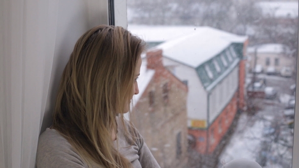 Woman Looking on Snowfall Through Out the Window
