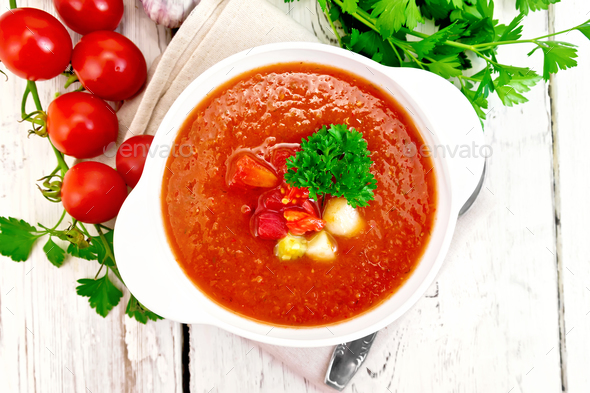 Soup tomato in white bowl with vegetables and parsley on board top - Stock Photo - Images