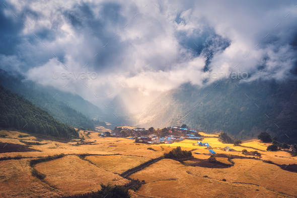 Village on the hill lighted by a sunbeam at sunset - Stock Photo - Images