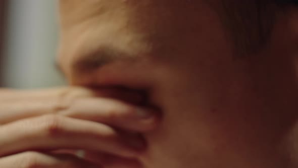 Tired Young Man is Rubbing His Eyes and Putting on Round Glasses alt