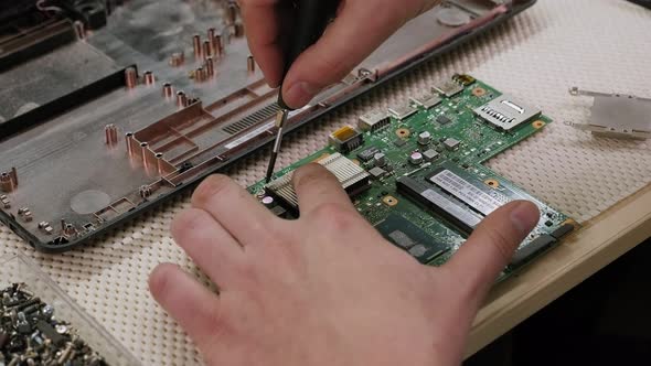A Man Repairs a Computer Removes an Electronic Circuit Board on a Desktop alt