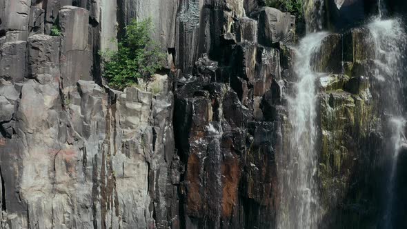 Aerial view waterfall with black columns on the sides of canyon