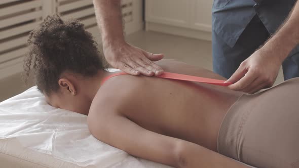 Physiotherapist Applying Kinesio Tapes to Patient Back alt
