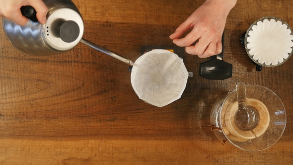 Barista pouring water on coffee ground with filter