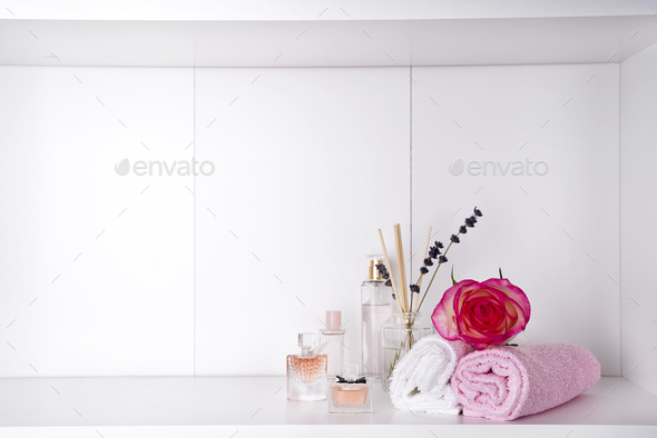 Stack of bath towels with rose and parfums on light background - Stock Photo - Images