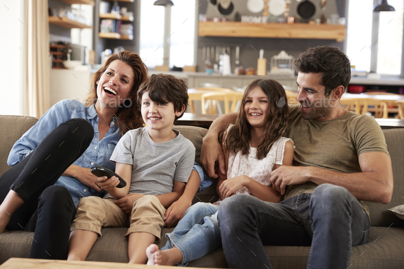 Family Sitting On Sofa In Open Plan Lounge Watching Television Stock Photo by monkeybusiness