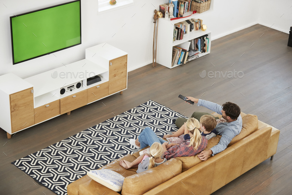 High Angle View Of Family Sitting On Sofa In Lounge Watching TV Stock Photo by monkeybusiness