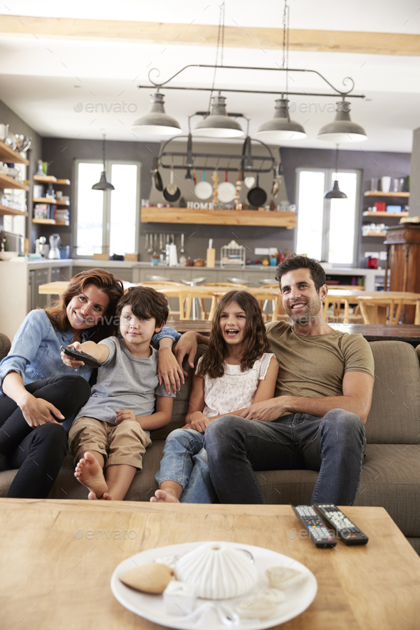 Family Sitting On Sofa In Open Plan Lounge Watching Television Stock Photo by monkeybusiness