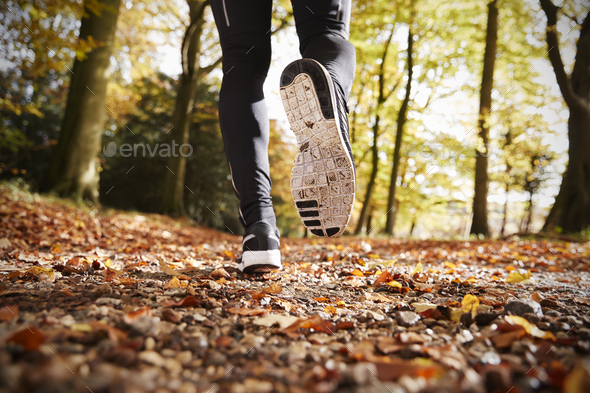 Close Up Of Male Runners Feet On Run Through Autumn Landscape Stock Photo by monkeybusiness