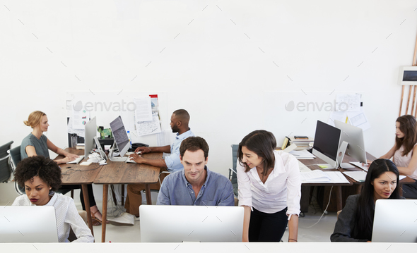 Colleagues talking at work in a busy open plan office Stock Photo by monkeybusiness