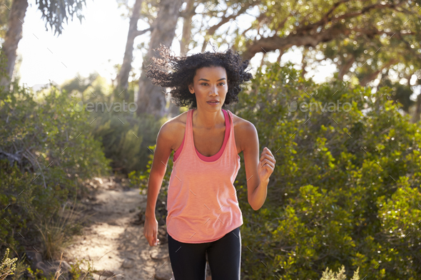 Young black woman jogging in a forest, close up Stock Photo by monkeybusiness