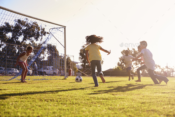 Girl defending goal at football game with family and friends Stock Photo by monkeybusiness
