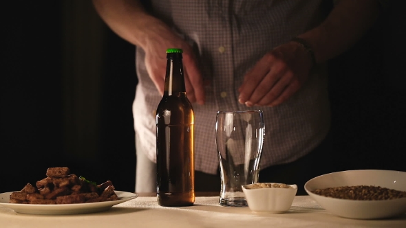 Man Pouring Beer Into Glass on Black Background