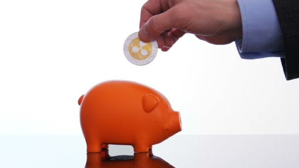 Businessman Hand Putting a Ripple Coin in a Piggy Bank