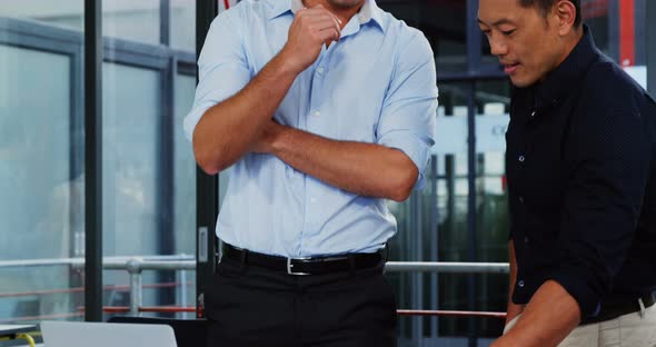 Business executives discussing over blueprint alt