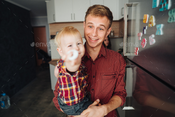 Dad and little son in the kitchen by the fridge Stock Photo by simbiothy
