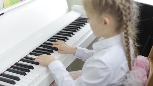 Child Plays Music on a White Piano