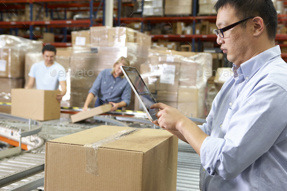 Worker Using Tablet Computer In Distribution Warehouse Stock Photo by monkeybusiness