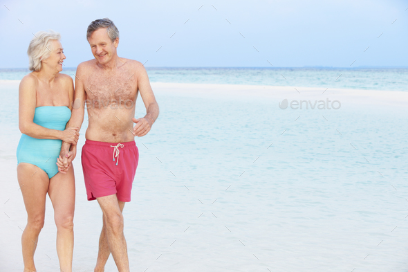 Senior Romantic Couple Walking In Beautiful Tropical Sea Stock Photo by monkeybusiness