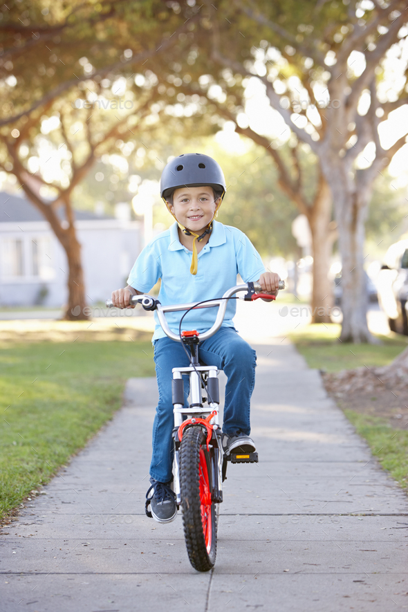 Boy Wearing Safety Helmet Riding Bike Stock Photo by monkeybusiness