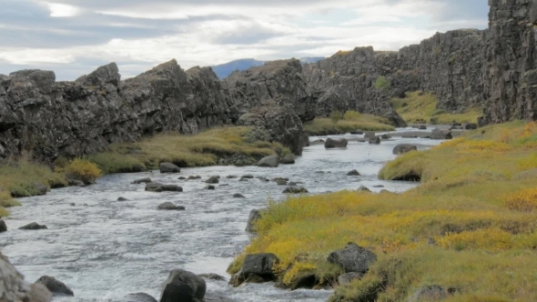 Dramatic Landscape with Small River Is Flowing Between Dark Basalt Rocks, in Cloudy Autumn Day