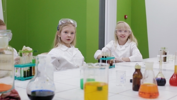 Group Of Kids Rise Hand In Chemistry Class
