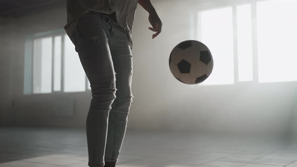 A Black Guy Trains with a Soccer Ball in an Underground Parking Lot in the Sunlight in Slow Motion alt