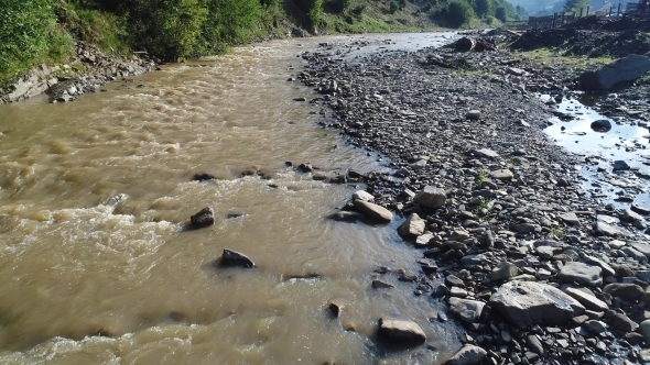 Mountain Stream with a Forest on One Side and a Village on the Other Side. Carpathians, Ukraine alt