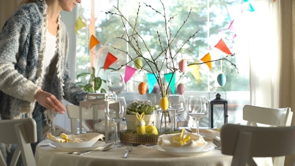 Young Woman Setting Easter Festive Table with Bunny and Eggs Decoration alt